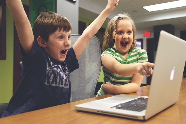 子供達がパソコンで放送されているサッカーの試合を見て喜んでいる