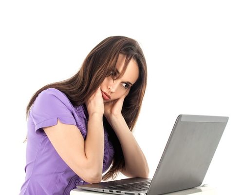 女性がパソコンを見ながら悩んでいる